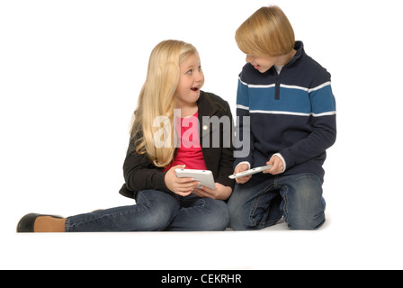 Ten year old girl and eleven year old boy using tablet computers or eBook readers and smiling. Stock Photo