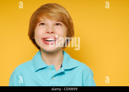 Cute eleven year old boy is smiling and looking up toward the top of the frame.