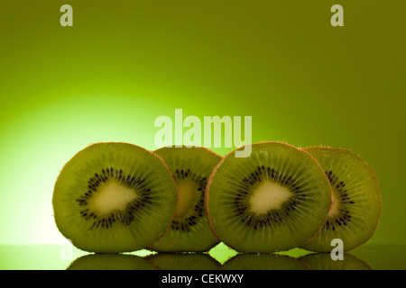 Green Kiwi in row on green background Stock Photo