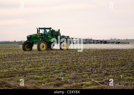 A John Deere sprayer applies pre-plant burndown herbicide in late Winter to a field that will be no-till planted to cotton. Stock Photo