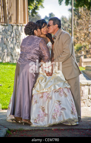 Parents in Cerritos, CA, kiss their formally-dressed daughter at her quinceanera, a common rite of passage for 15 year old girls Stock Photo