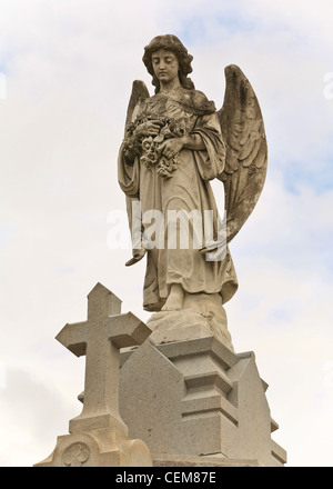 Statue of Angel and Cross with blue and white sky in background Stock Photo