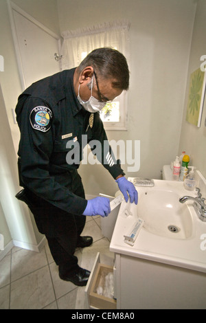 Wearing a mask to avoid contaminating the area, a Pakistani-American police crime scene investigator checks for DNA evidence. Stock Photo