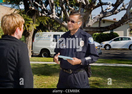 After gathering forensic evidence on break-in, Pakistani-American police crime scene investigator talks with the owner of  home Stock Photo