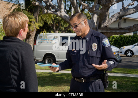 After gathering forensic evidence on break-in, Pakistani-American police crime scene investigator talks with the owner of  home Stock Photo