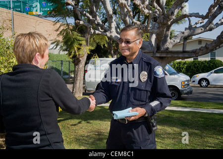 A Pakistani-American police crime scene investigator shakes hands with a homeowner after collecting evidence after a break-in. Stock Photo