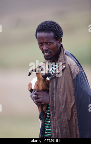 Ethiopian Shepherd carrying a newborn lamb. Stock Photo