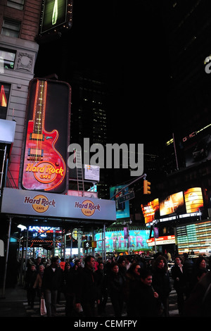 Night neon portrait people crossing West 43rd Street, below Hard Rock Cafe red guitar sign, 7th Avenue, Times Square, New York Stock Photo