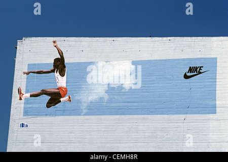 Retro image of Nike Ad Carl Lewis iconic athlete doing his long jump side of building painted mural Stock Photo