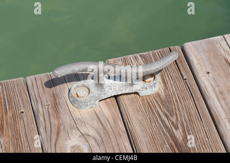 old iron mooring cleat on a wooden pier (green lagoon) Stock Photo