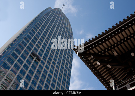 Window cleaners in a cradle on the Atago Green Hills tower, above part of a shrine roof. Tokyo, Japan. Stock Photo