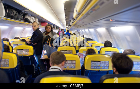 Ryanair cabin with passengers standing in the air luggage in racks Stock Photo