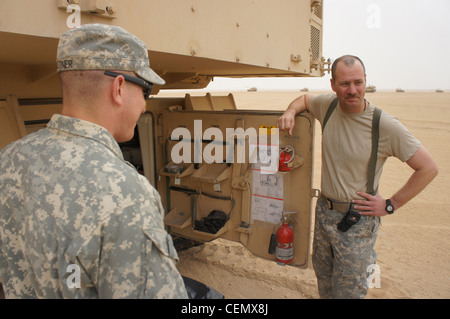 Sgt. Micha Pohlman and Spc. Shawn Kastner of the 1st Brigade Combat Team, 34th Infantry Division's 1-125 Field Artillery B Btry, stand beside a Paladin during a live fire exercise in northern Kuwait Feb. 16. Stock Photo