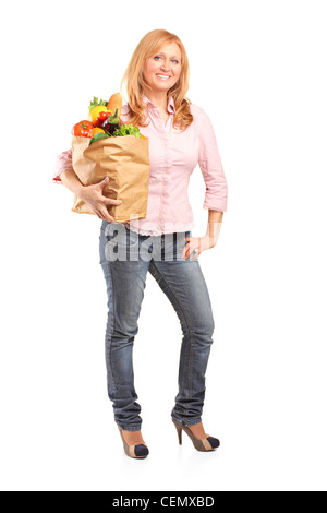 Full length portrait of a smiling woman holding a paper bag full of groceries isolated on white background Stock Photo