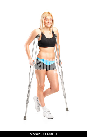 Full length portrait of an injured young female on crutches isolated on white background Stock Photo