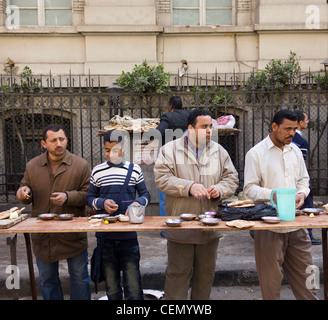 men and boy eating food at roadside stall, Cairo, Egypt Stock Photo