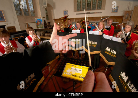 A small brass band group in rehearsal, with detail of band leaders hands and baton. Stock Photo