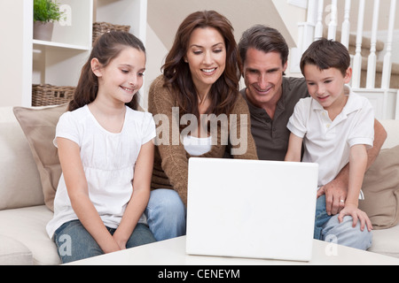 Happy family, parents, son and daughter, having fun using laptop computer together at home on a sofa. Stock Photo