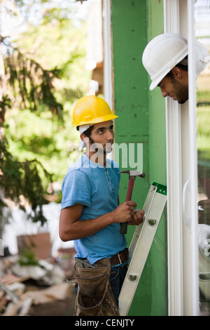 Hispanic carpenter inspecting installation of new window frame Stock Photo