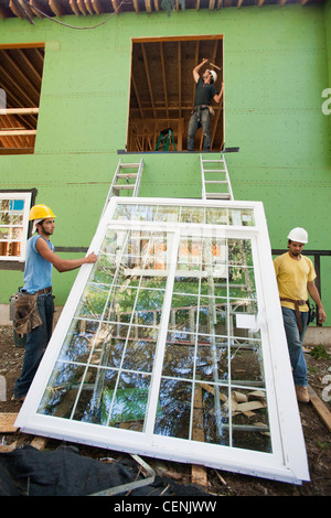 Hispanic carpenters preparing to Hoist, Window frame to second floor Stock Photo