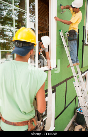 Hispanic carpenters nailing and installing flashing around window frame Stock Photo