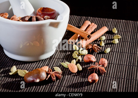 Nuts and cinnamon sticks in front of a mortar Stock Photo