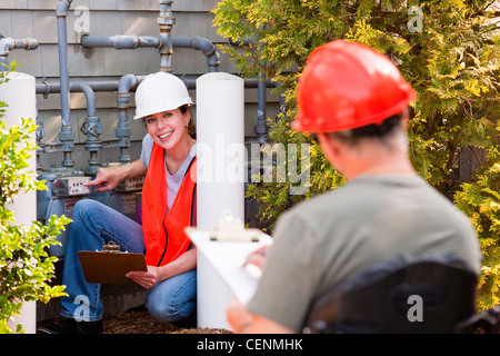 Engineer in wheelchair discussing energy efficiency data with female engineer in front of gas meter Stock Photo
