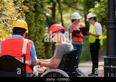 Architects in wheelchairs discussing data before meeting with project engineers Stock Photo