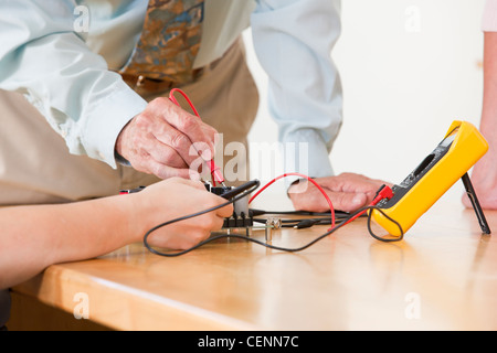 Engineering professor assisting student with multimeter measurement on circuit board Stock Photo