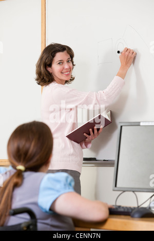 Students in computer classroom writing on whiteboard Stock Photo