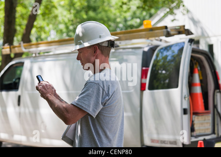 Cable installer reviewing work order for installation on smartphone Stock Photo