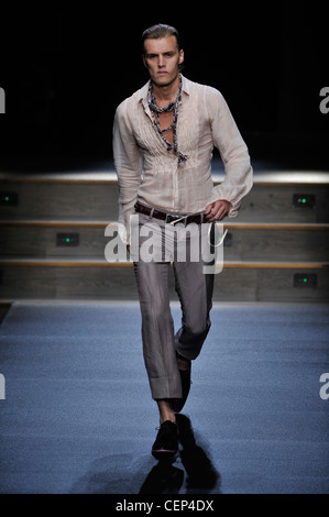 Byblos Milan Ready to Wear Spring Summer Model wearing narrow legged cropped grey trousers, brown leather belt, ruched front Stock Photo