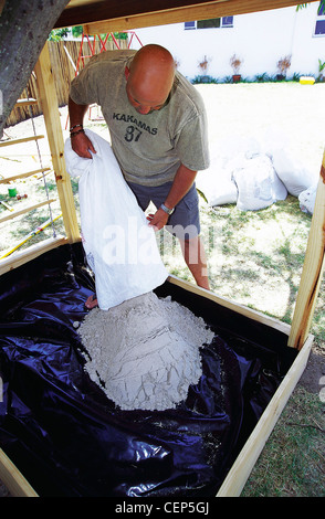 FORBuild a Tree House Step Male filling the sand pit underneath the tree house with sand Stock Photo