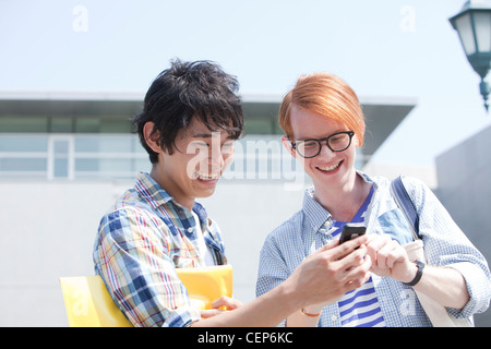 Two young men using Smartphone at campus Stock Photo