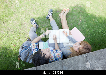 Young man and woman sitting on lawn and looking up Stock Photo