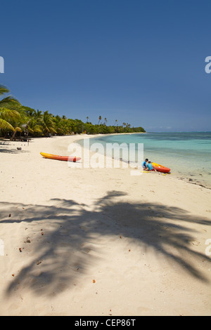 Palm tree shadow and family playing on beach, Plantation Island Resort, Malolo Lailai Island, Mamanuca Islands, Fiji Stock Photo