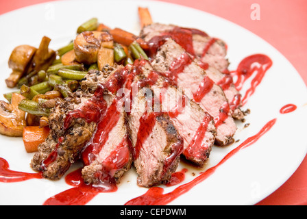 Roasted Beef meat at cranberries sauce with roasted vegetables in cognac Stock Photo
