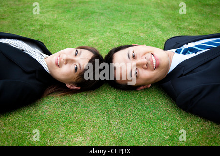 Attractive young adult couple and lay on the grass field Stock Photo