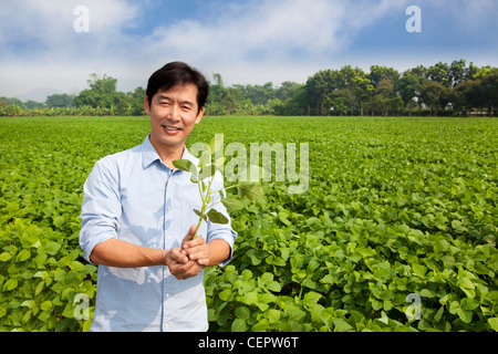 chinese farmer holding sapling and standing on his farm Stock Photo