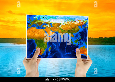 Hand holding map at beauty sunset on Lake, and orange sky Stock Photo