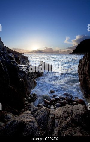 Sunset over the sea viewed from Porth Nanven, a beach sometimes referred to as 'Dinosaur Egg Beach' because of large deposit of Stock Photo