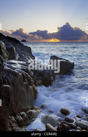 Sunset over the sea viewed from Porth Nanven, a beach sometimes referred to as 'Dinosaur Egg Beach' because of large deposit of Stock Photo