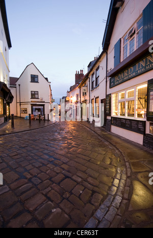 Traditional cobbled street winding towards the Board Inn pub in Whitby. Stock Photo