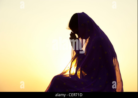 Indian teenage girl praying at sunset covered by a star veil. Silhouette. India Stock Photo