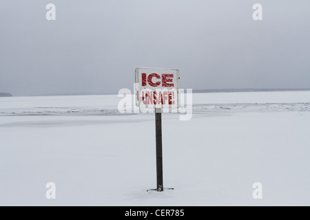A sign on a frozen lake that reads "ice unsafe". Stock Photo