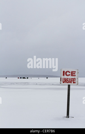 A sign on a frozen lake that reads "ice unsafe". Stock Photo