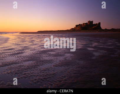 Bamburgh Castle at dawn from the magnificent wide beach. Built on a basalt outcrop, the first written reference to it is in 547 Stock Photo