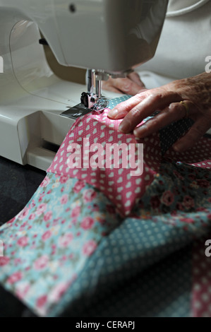 Mature woman in her 70s using a Janome sewing machine making a quilt at home UK Stock Photo