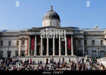People sitting on steps outside The National Gallery in Trafalgar Square. Stock Photo