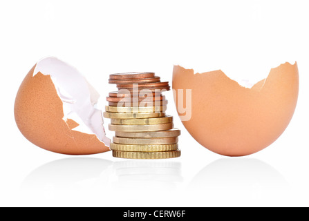 Broken egg shell with coins between on a white background with a shadow underneath Stock Photo